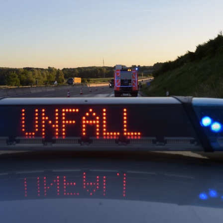 Auf einem Polizeifahrzeug warnt auf der Autobahn eine Leuchtschrift vor einer Unfallstelle.