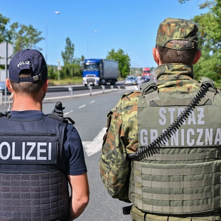 Ein deutscher Polizist und sein polnischer Kollegen stehen an einem Autobahngrenzübergang