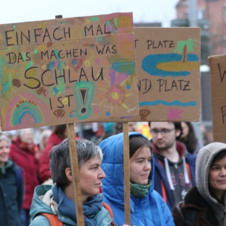 Menschen halten ihre Schilder auf einer Fridays for Future Demo.