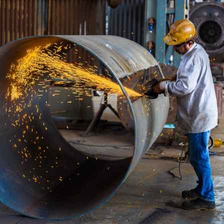Fabrikarbeiter bei der Arbeit an einen großes Metallrohr. Funken schlagen