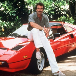 Privatdetektiv Thomas Magnum lehnt an einem roten Ferrari in der Fernsehserie Magnum.