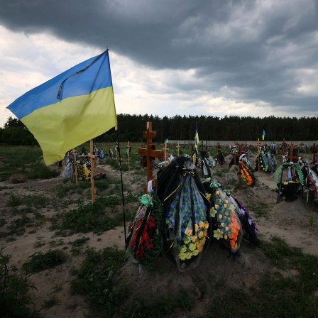 Eine ukrainische Flagge weht auf einem Friedhof in der Ukraine © picture alliance/ AP/ Kunihiko Miura