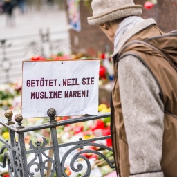 Eine Frau steht im Februar 2020 auf dem Marktplatz von Hanau, wo die Bürger mit Blumen, Plakaten und Kerzen ihre Trauer zum Ausdruck bringen. Auf einem Schild steht: "Getötet, weil sie Muslime waren!"