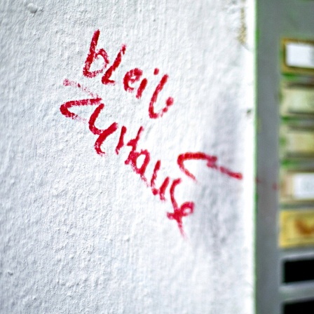 Neben einer Klingelleiste steht mit rotem Marker auf die weiße Wand geschrieben: "Blieb zu Hause"