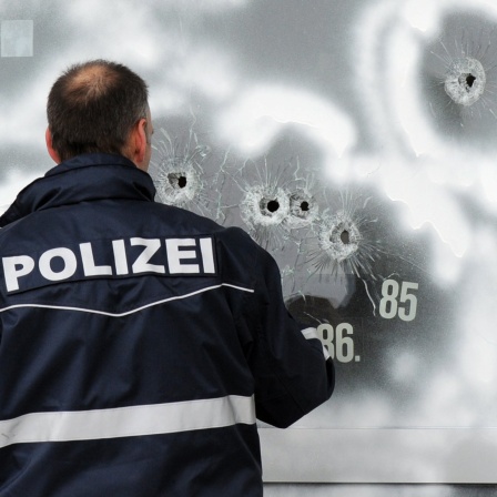 Einschusslöcher einer großkalibrigen Waffe markiert ein Polizist am 12.3.2009 in der Scheibe eines Autohauses in Wendlingen mit weißer Farbe. Auf dem Hof des Autohauses endete der Amoklauf eines 17-Jährigen, der zuvor 15 Menschen erschossen hatte, bevor er seinem Leben selbst ein Ende setzte.
