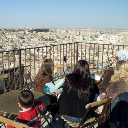 Aleppo vor dem Krieg. Frauen sitzen auf einer Dachterasse und schauen über die Stadt.