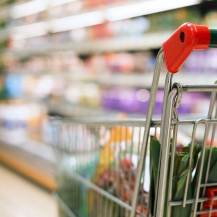 Ein Mann schiebt einen Einkaufswagen durch den Supermarkt. 