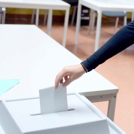 Symbolbild: Ein junger Mensch wirft einen Wahlschein in eine Wahlurne.