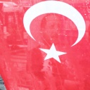Frau mit Regenschirm läuft an einer türkischen Fahne vorbei. Symbolbild