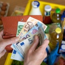 Portemonnaie und Geldscheine über einer Einkaufskiste mit Lebensmitteln