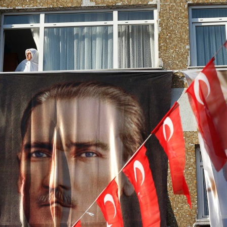 Eine Frau blickt aus einem Fenster hinter einem Banner des türkischen Staatsgründers Atatürk (l) und des türkischen Präsidenten Erdogan