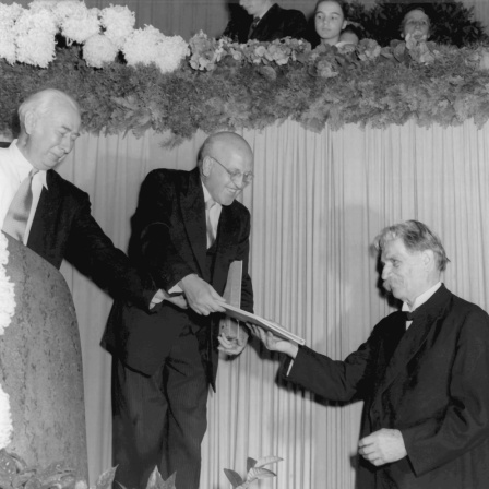 Am 16. September 1951 wurde Albert Schweitzer (rechts) in der Frankfurter Paulskirche mit dem Friedenspreis des Deutschen Buchhandels ausgezeichnet. Bundespräsident Theodor Heuss (links) überreicht ihm die Urkunde. In der Mitte der Vorsitzende des Börsenvereins des Deutschen Buchhandels, Dr. Josef Knecht.