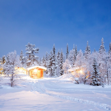 Beleuchtete Hütte in weißer Winterlandschaft: Schnee ist weiß, obwohl Wasser durchsichtig ist