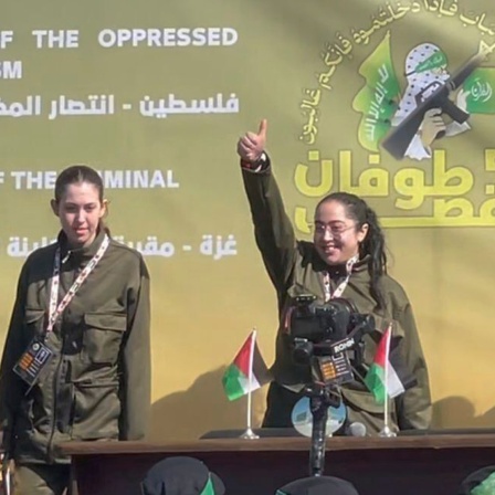Vier israelische Soldatinnen stehen vor einer palästinensischen Menschenmenge.

