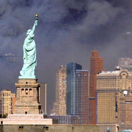Blick auf die Freiheitsstatue vor schwarzem Rauch, der nach dem Anschlag auf das World Trade Center am 11.9.2001 in New York aus den Trümmern der eingestürzten Zwillingstürme aufsteigt.
