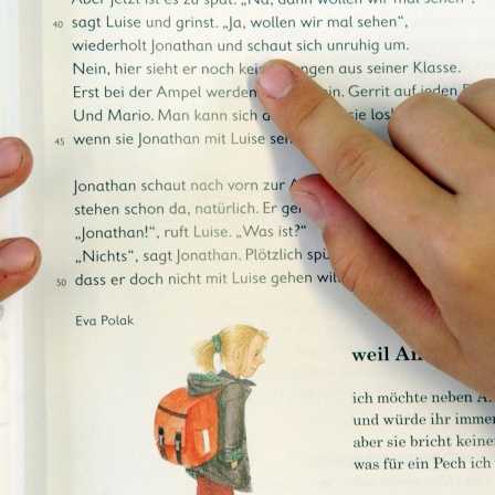  Buchstabe für Buchstabe gleiten die Finger eines Schülers über die Buchseite beim Deutschunterricht der dritten Klasse 