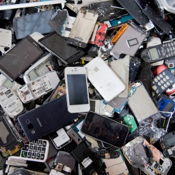 Alte Handys und Smartphones liegen in einem Container, ehe sie geschreddert werden. Verbraucherinnen und Verbraucher können alte Elektro-Kleingeräte auch in den meisten Supermärkten und Discounter-Filialen zurückgegeben.