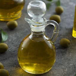 Hohe Ansicht auf eine Flaschen, gefüllt mit Olivenöl, auf einem Marmor Hintergrund. 