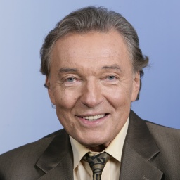 Karel Gott: Der Sänger lächelt und trägt einen hellbraunen Anzug und eine Krawatte in derselben Farbe.