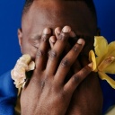 Ein Mann hält sich seine Hände mit Blumen vors Gesicht