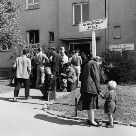 Schlange im Notaufnahmelager Marienfelde am 1. September 1958 in West-Berlin. Das Aufnahmelager für Flüchtlinge aus der DDR und Ost-Berlin war 1952 / 1953 erbaut worden. Ende August 1958 erreichten die Flüchtlingszahlen mit 3.000 Menschen innerhalb von drei Tagen eine neue Rekordhöhe: Blick auf die Reihe von Menschen, die im Notaufnahmelager Marienfelde auf ihre Registrierung warten.