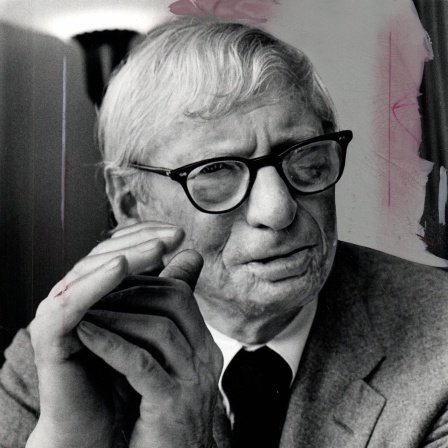 Schwarzweißporträt von Louis Kahn. Ein älterer Mann mit Brille und im Anzug, der alte Brandnarben an Wange und Kinn hat.