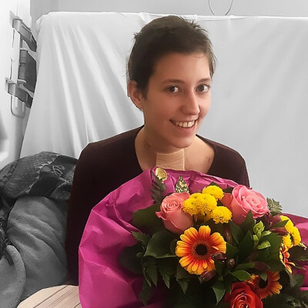 Luisa sitzt mit einem Blumenstrauß in ihrem Krankenbett