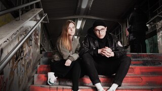 Die Hosts Anja Buwert und Jan Karon sitzen auf einer Treppe; Schriftzug "Schattenwelten Berlin" (Quelle: rbb/PQPP2 GmbH)