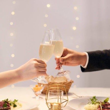 Mann und Frau stoßen mit Champagner an.