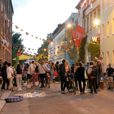Menschen in einer mit Wimpeln geschmückten Straße.
