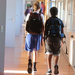 Jugendliche mit Schulrucksack in einem Schulflur.