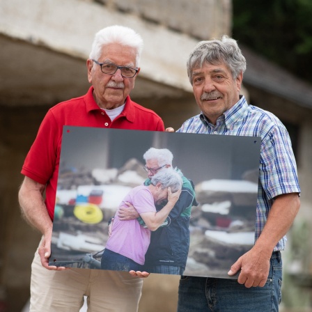 Zwei Brüder stehen am ehemaligen Standort ihres bei der Flut zerstörten Elternhauses in Altenahr-Altenstadt