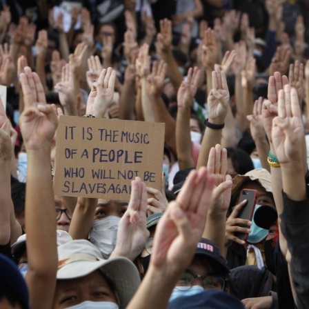 Proteste in Bangkok, Thailand. Die Menschen halten die Hände mit dem Drei-Finger-Gruß in die Luft, 16. August 2020.
