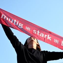 Eine junge Frau hält einen Schal mit dem Motto des Evangelischen Kirchentags: mutig, stark, beherzt