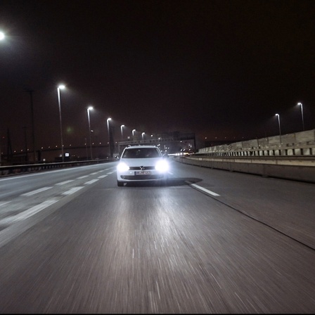 Ein Auto der Marke VW fährt nachts auf einer Schnellstraße.