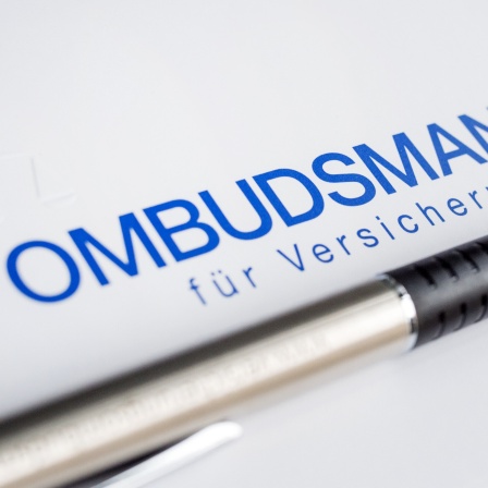 Ein Kugelschreiber liegt unter dem Schriftzug "Ombudsmann für Versicherungen".