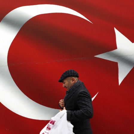 Ein Mann geht an einer türkischen Flagge vorbei. Symbolbild
