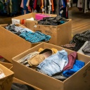 Kisten mit gebrauchter Kleidung warten in einem Secondhand-Laden in New York darauf, preislich bewertet und sortiert zu werden.