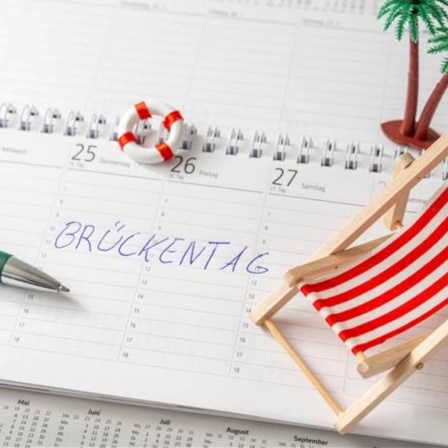 "Brückentag" geschrieben auf einem Kalender mit einem Liegestuhl und einer Palme