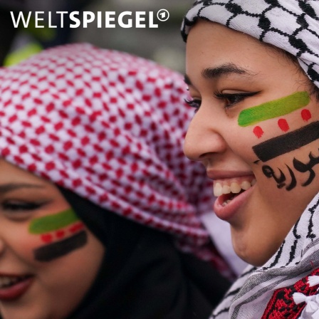 Frauen mit Kopftuch und auf die Wange gezeichnete Fahne feiern, nach dem Sturz der Regierung des syrischen Präsidenten Assad auf dem Trafalgar Square.