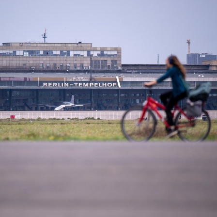 Eine Fahrradfahrerin fährt über das Rollfeld auf dem Gelände des ehemaligen Flughafens Berlin-Tempelhof.