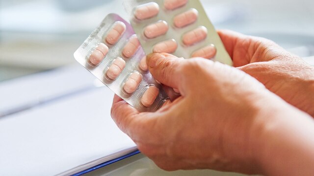 Ein Arzt hält eine Blisterverpackung mit Tabletten in der Hand.