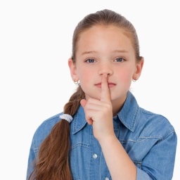 Ein Mädchen legt den Zeigefinger auf seine Lippen