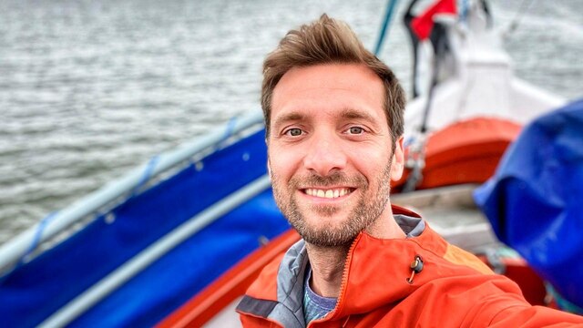 Daniel Paßmann steht auf einem Boot und lächelt in die Kamera.
