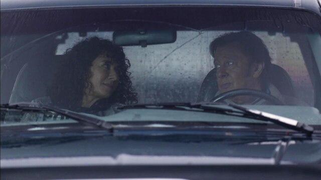 Maria Ketikidou und Jan Fedder sitzen in einem Auto und schauen sich an.