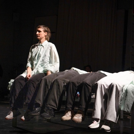 Szenenbild aus der Performance "Turn the Page". Vier Frauen liegen auf einem Tisch, eine davon richtet sich auf.