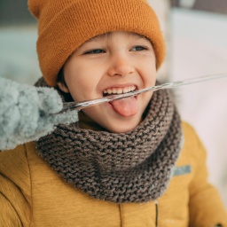 Junge im Winter leckt an einem Eiszapfen