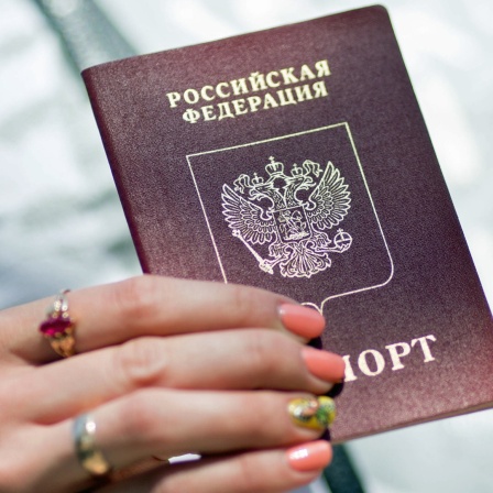 Eine Frau hält ihren russischen Pass in den Händen.