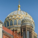 Synagoge in der Oranienburger Straße in Berlin-Mitte. Die goldverzierte Kuppel glänzt im Sonnenschein vor strahlend blauem Himmel