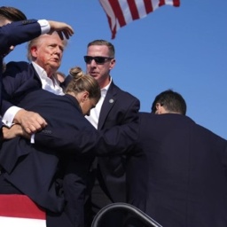 Mitarbeiter des Secret Service stehen schützend um Trump, der mit Blut an Ohr und Wange am Rednerpult steht